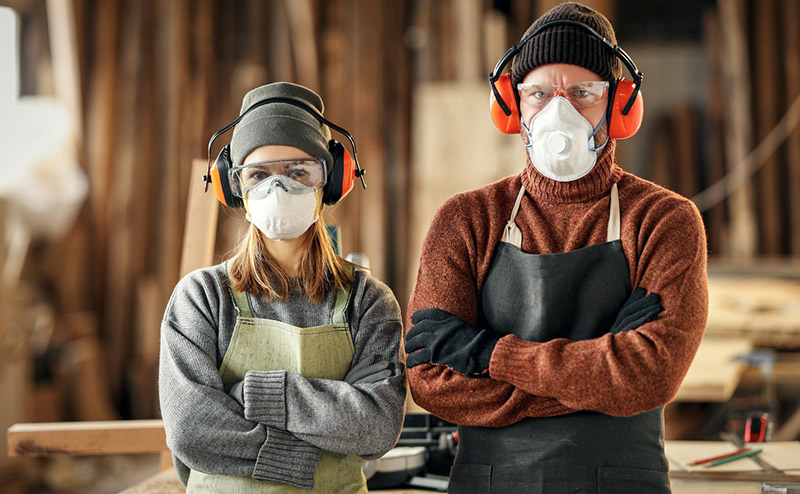 Woodworkers in protective masks and headphones